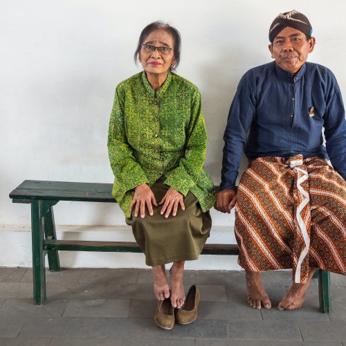 Java Island, Indonesia - August, 14 2015: Barefoot people on bench in palace yard