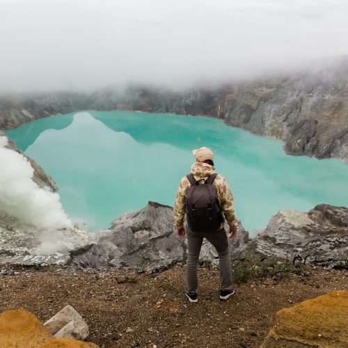 Man tourist looks at the sulphur lake on the Ijen volcano on the island Java in Indonesia.